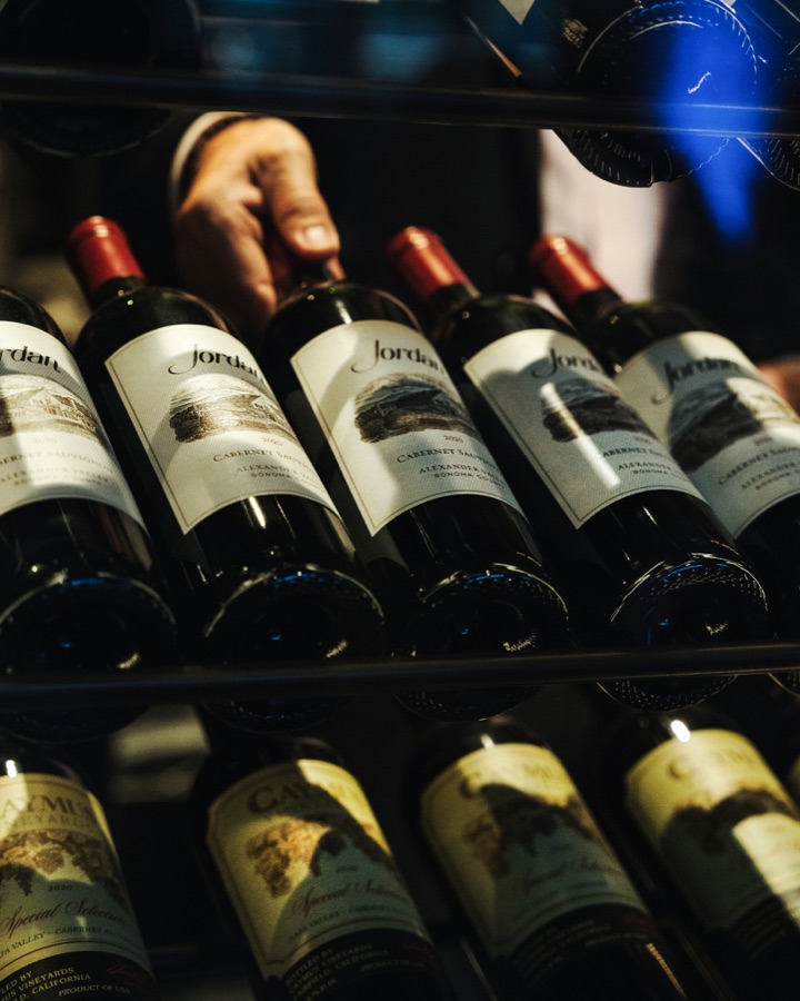 Hand pulling a bottle from the wine wall