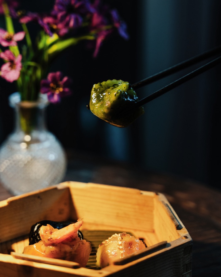 A bite held over a wooden box, flowers behind